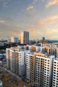 High-rise apartment buildings under construction in a city skyline at sunset.