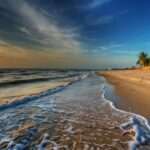 Sunset over a tranquil Thai beach with palm trees, golden sands, and gentle waves, perfect for relax.