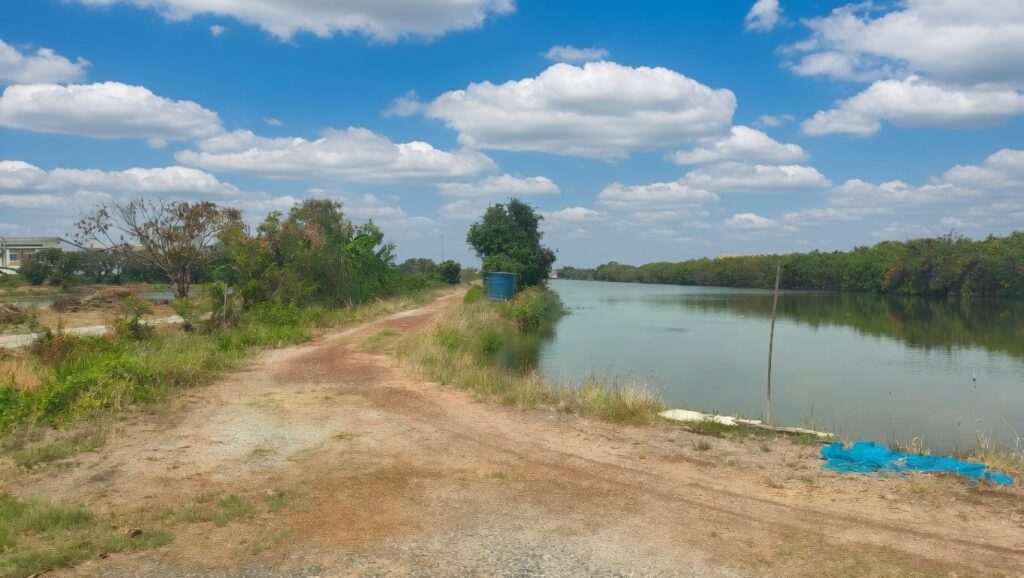 Scenic rural landscape with dirt road and river, ideal for building your Thai dream house.