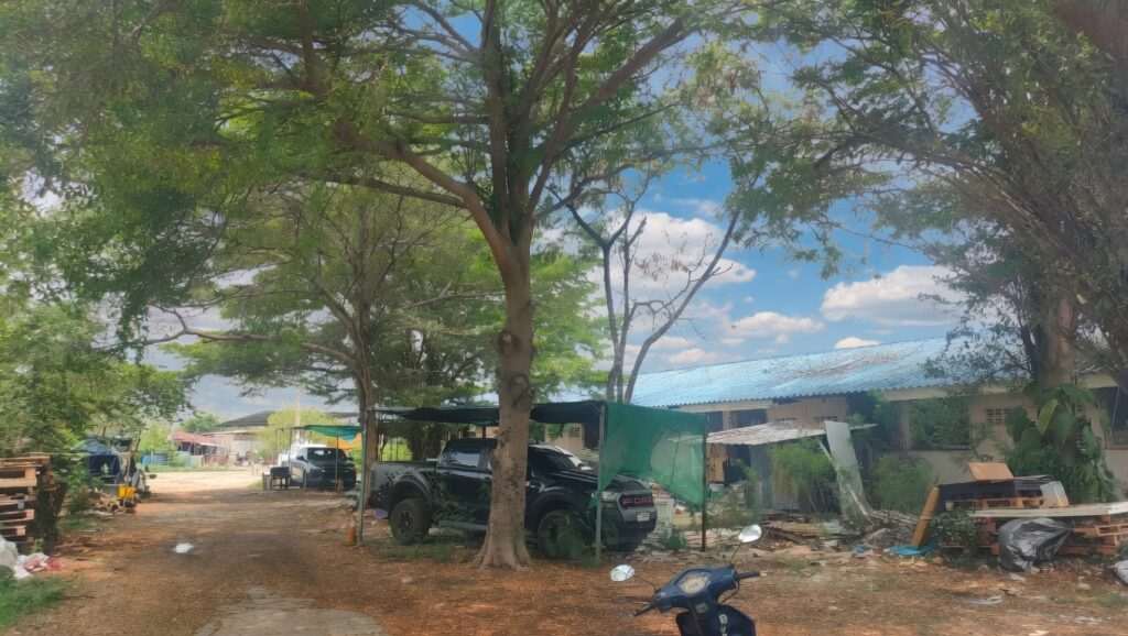 Rural Thai house with trees and makeshift structures, promoting homeownership dreams in Thailand.